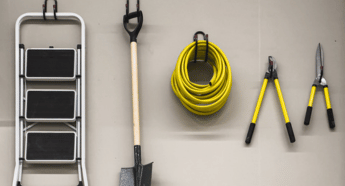 Slatwall hooks neatly holding garden tools in a shed for organized storage.