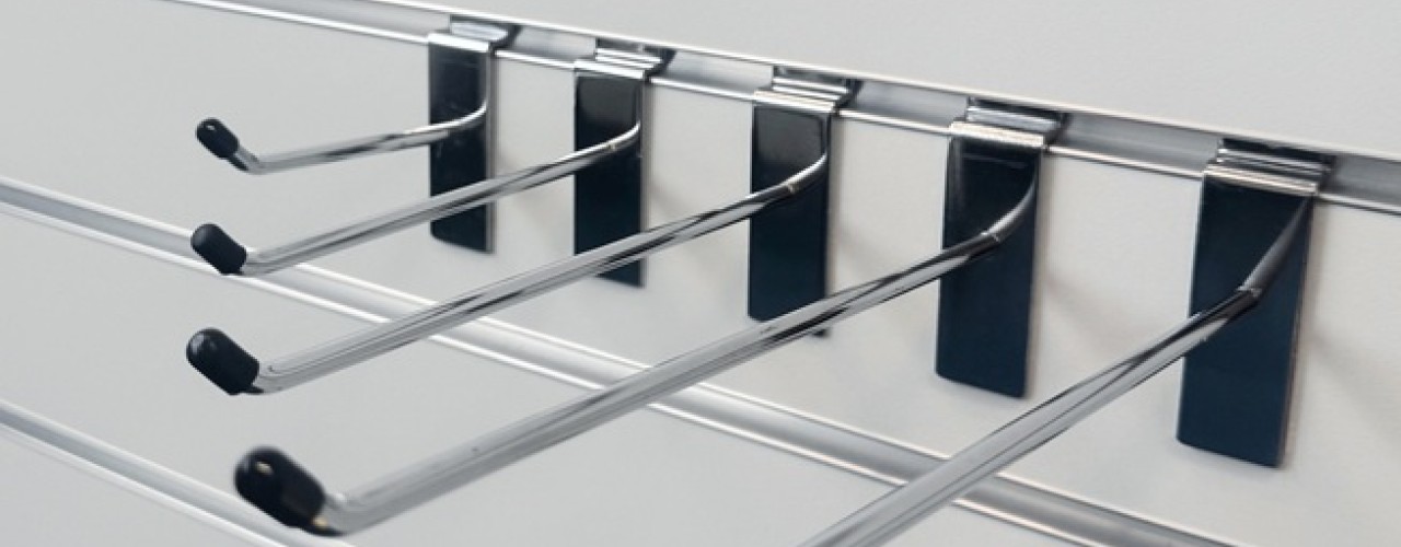 A metal rack featuring multiple slatwall hooks and a horizontal rod for hanging items.